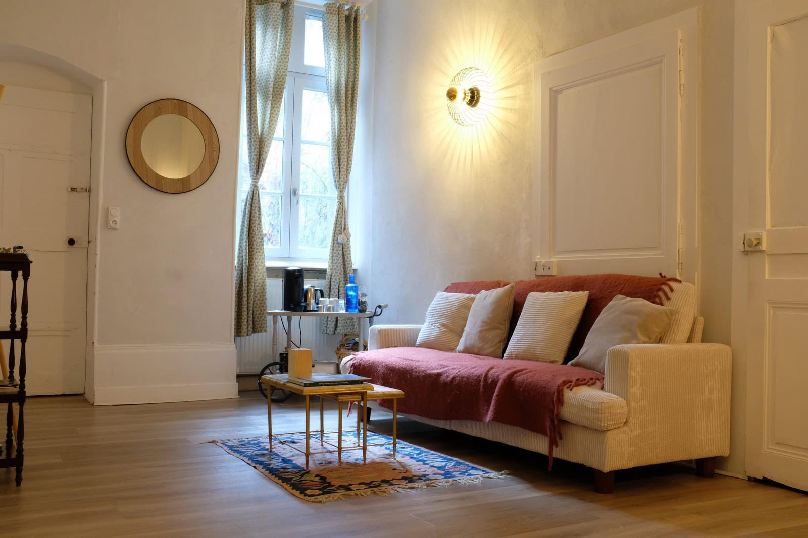 Salon spacieux avec miroir rond et grande fenêtre